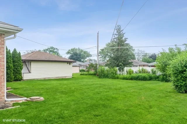 a backyard of a house with plants and large tree