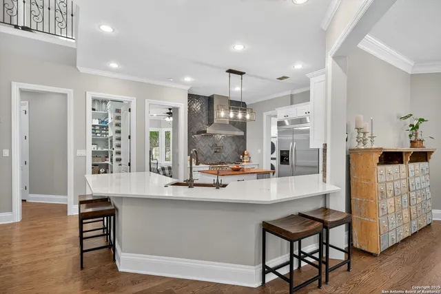 a kitchen with stove a sink dishwasher and a dining table with wooden floor