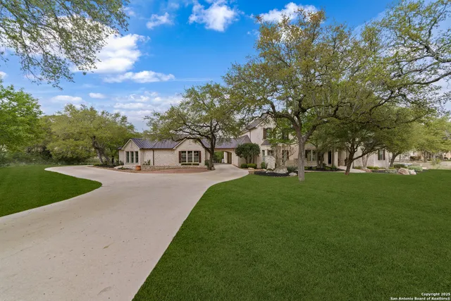 a view of a white house with a big yard and large trees