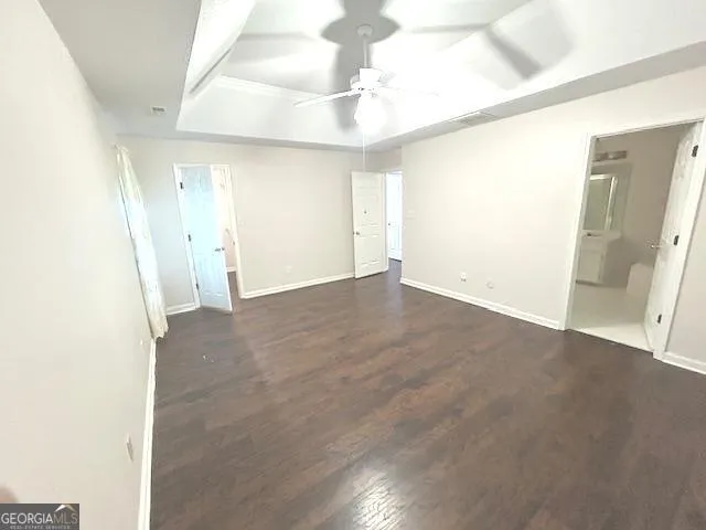 an empty room with wooden floor ceiling fan and windows