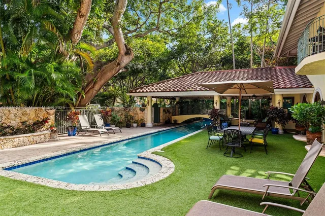 a view of a swimming pool with lawn chairs under an umbrella
