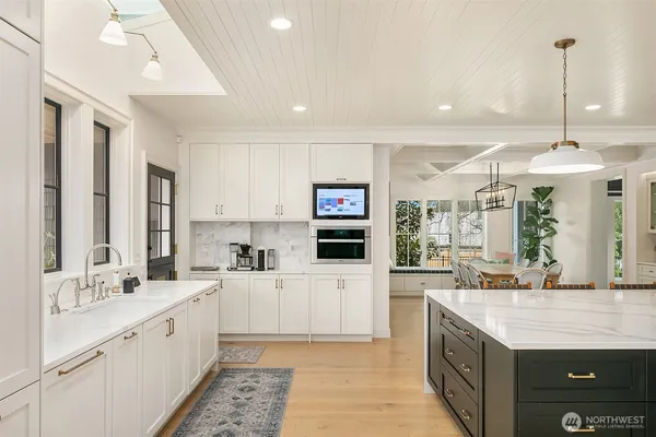 a large white kitchen with a sink and dishwasher with a large window