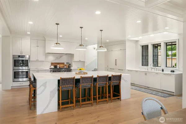a kitchen with stainless steel appliances granite countertop a stove a refrigerator a kitchen island a dining table and chairs with wooden floor