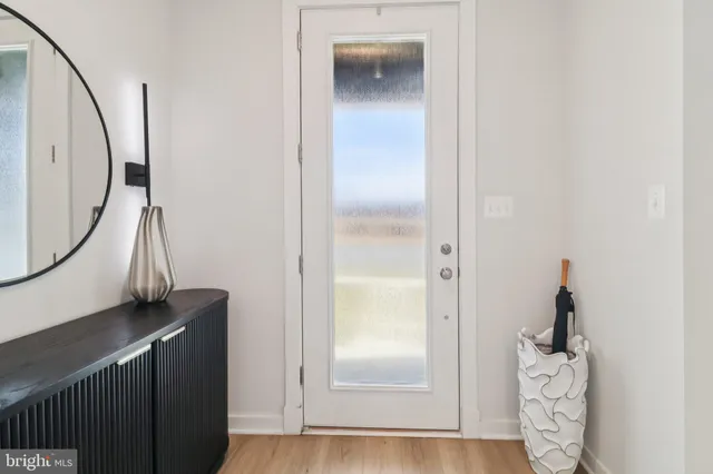 an entryway with wooden floor and a mirror