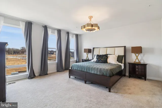 a bed sitting in a bedroom next to a window and a chandelier