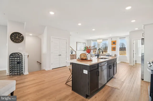 a living room with stainless steel appliances furniture a refrigerator and kitchen view