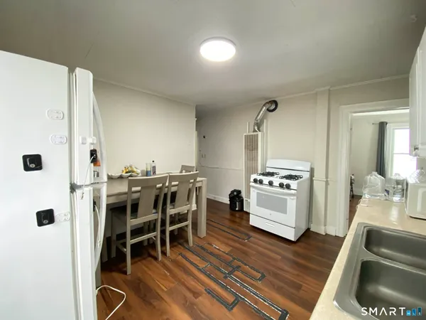 a kitchen with stainless steel appliances kitchen island granite countertop a table chairs and a refrigerator