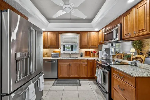 a kitchen with stainless steel appliances granite countertop a stove top oven a sink dishwasher a dining table and chairs with wooden floor