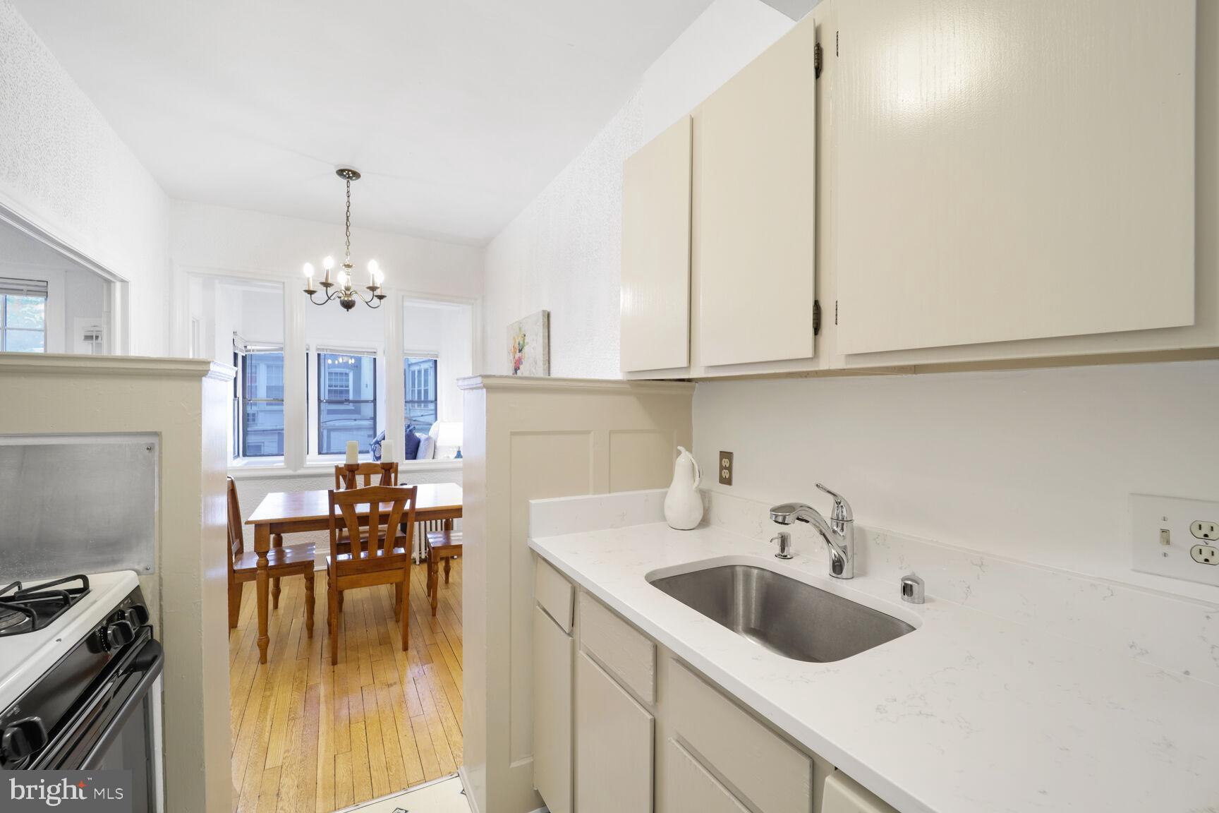 2032 Belmont Road Northwest, Unit 336 Washington, DC 20009 - Photo 11 of 23 a kitchen with sink cabinets and dining table chair