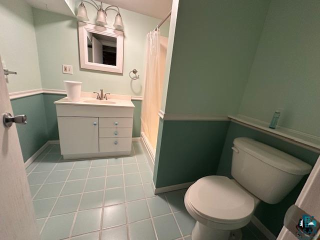 62 Elm Boulevard Babbitt, MN 55706 - Photo 17 of 21 Bathroom featuring baseboards, toilet, a shower with shower curtain, tile patterned floors, and vanity
