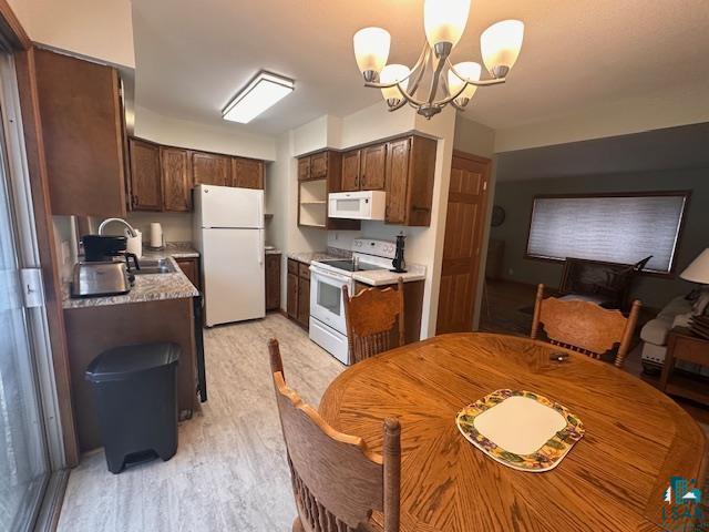 62 Elm Boulevard Babbitt, MN 55706 - Photo 3 of 21 Kitchen featuring white appliances, light countertops, an inviting chandelier, and a sink