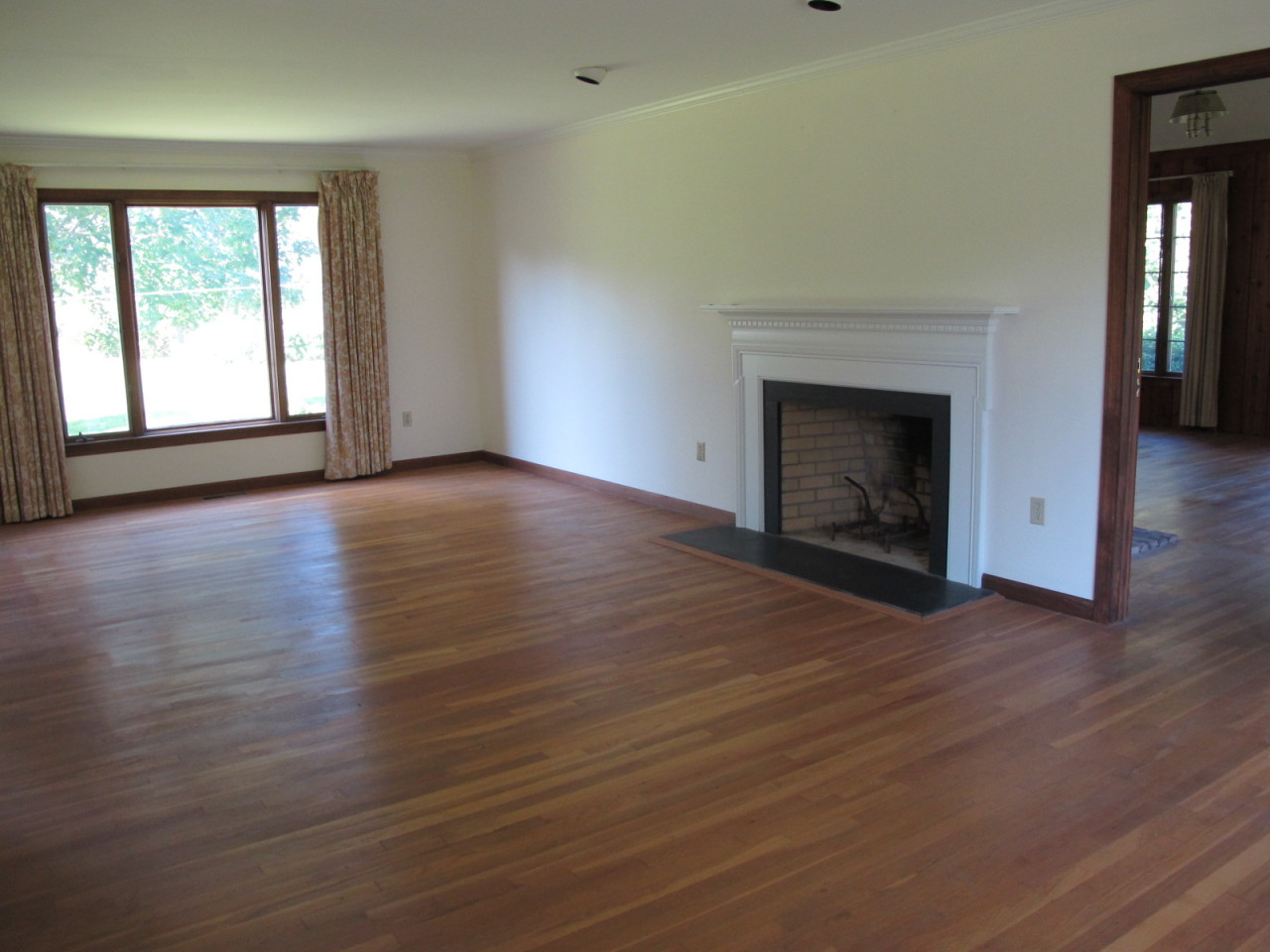 127 Middle Ridge Road New Canaan, CT 06840 - Photo 2 of 9 an empty room with wooden floor fireplace and windows