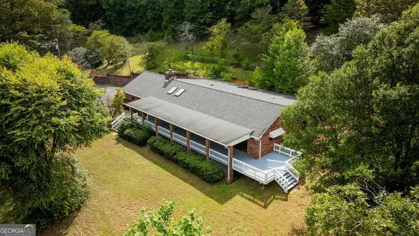 an aerial view of a house with swimming pool and large trees