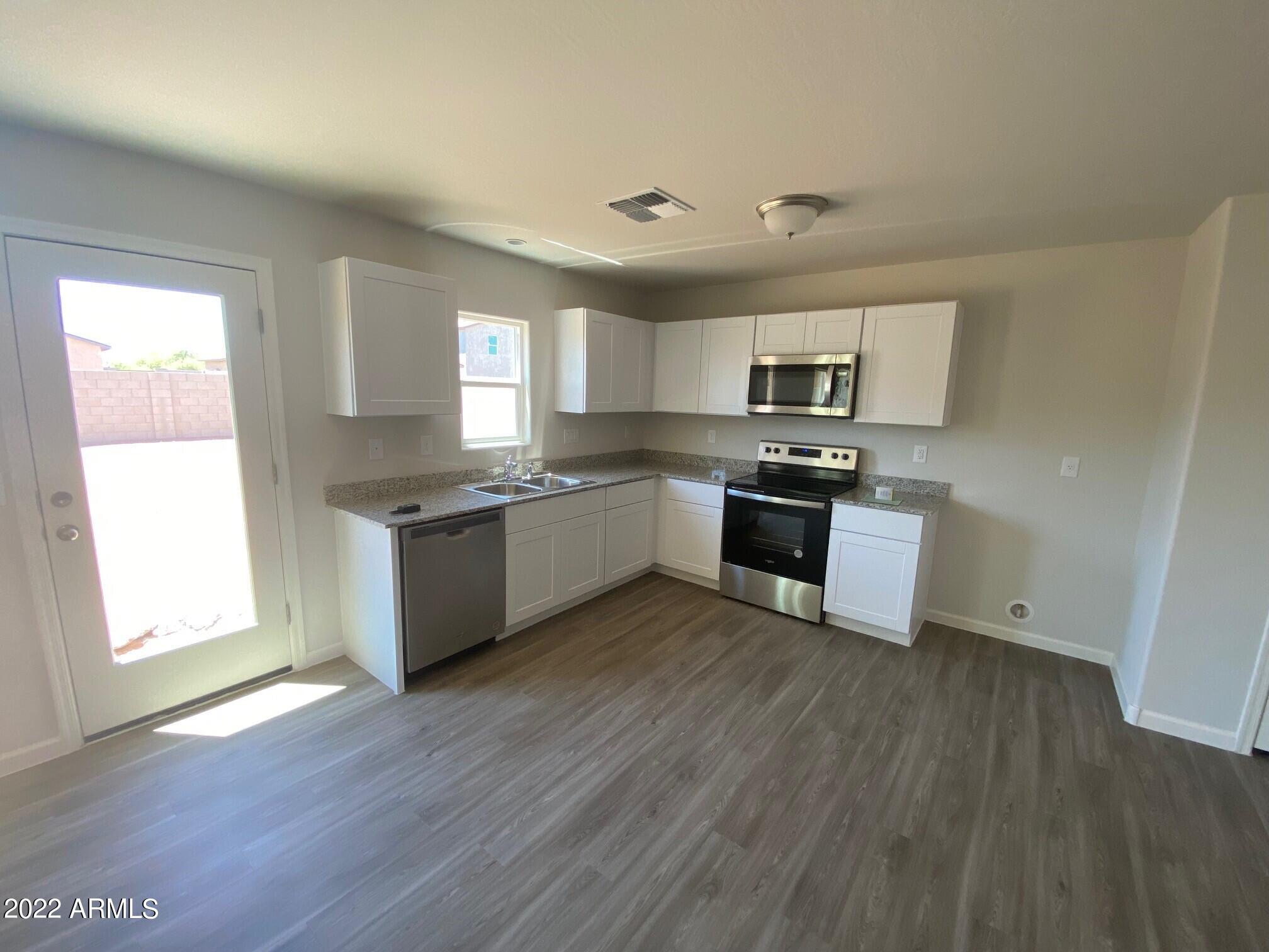 119 Dewey Avenue Coolidge, AZ 85128 - Photo 3 of 15 a kitchen with granite countertop wooden floors and white stainless steel appliances