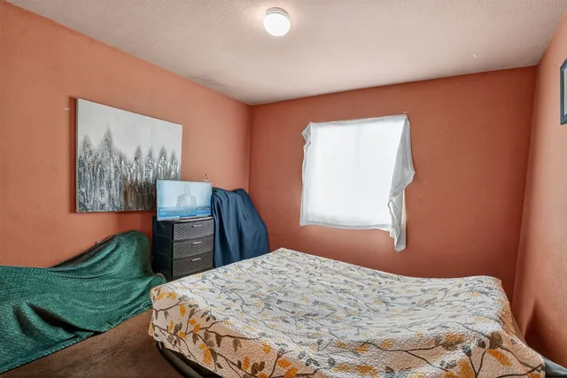 a bedroom with a bed and a dresser next to a window