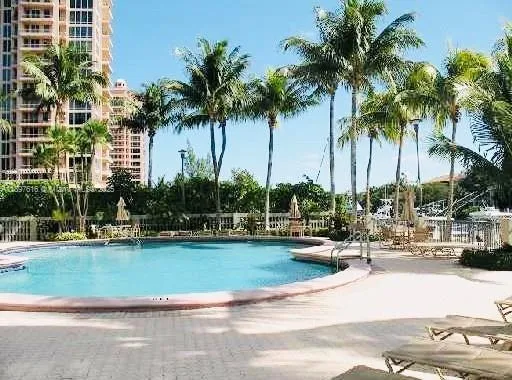 a view of a swimming pool with a lawn chairs and palm trees
