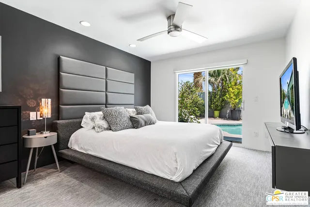 a bedroom with a bed and a flat tv screen on dresser