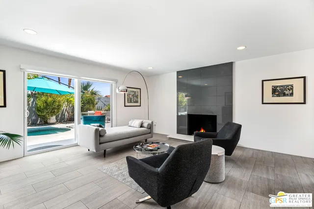 a living room with furniture two large window and a flat screen tv