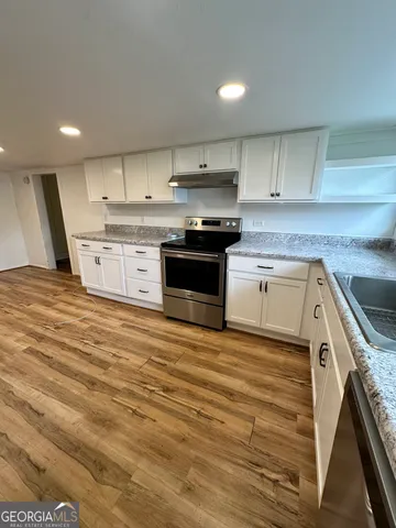 a large kitchen with stainless steel appliances granite countertop a stove and a sink
