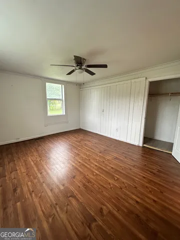 an empty room with wooden floor a ceiling fan and windows
