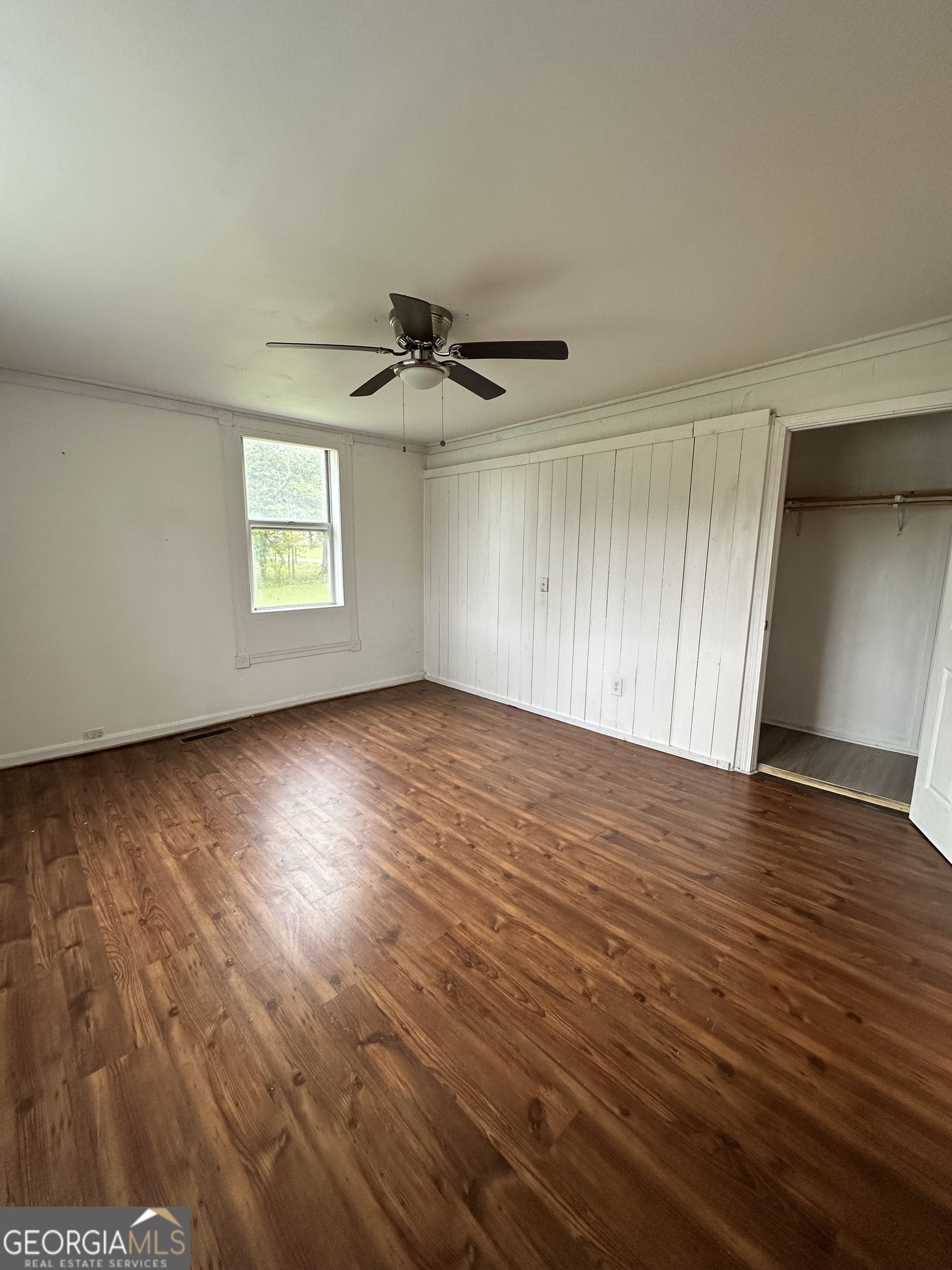 55 Bowdon Street Waco, GA 30182 - Photo 16 of 18 an empty room with wooden floor a ceiling fan and windows