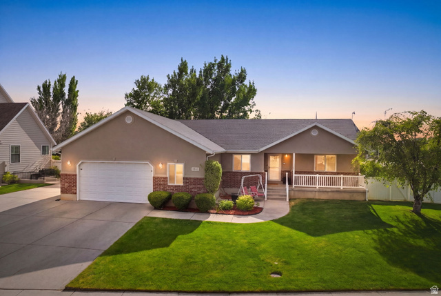1816 River Bottom Road Springville, UT 84663 - Photo 1 of 37 Single-story residence featuring a two-car garage, front porch with white railing, stucco and brick facade, a mature front yard tree, and a concrete driveway