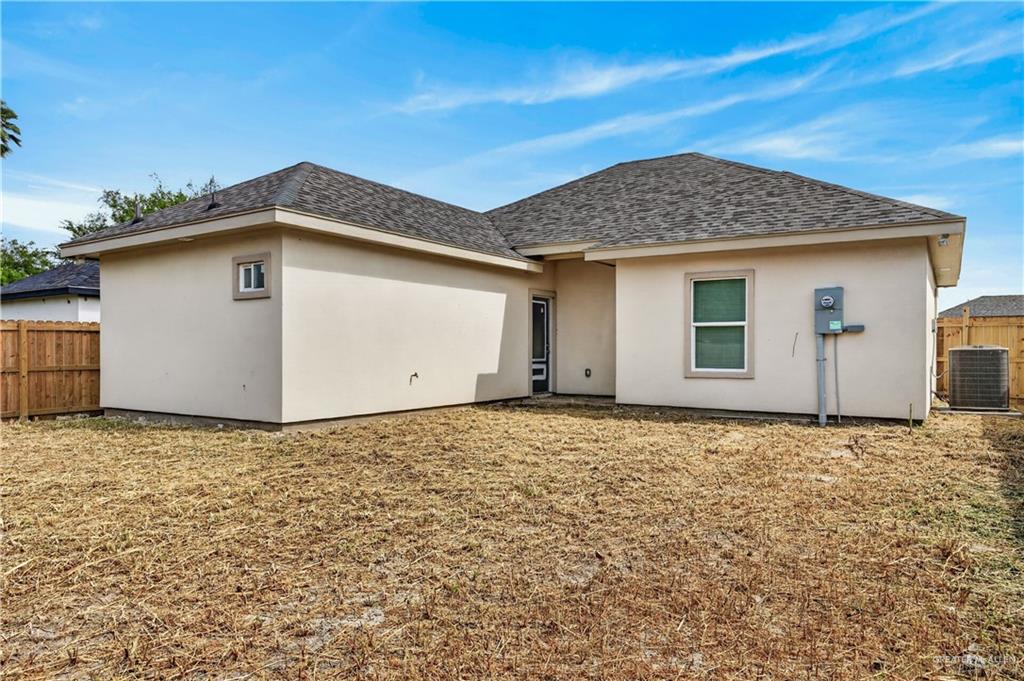 1920 Trinity Street Donna, TX 78537 - Photo 22 of 23 Rear exterior showcasing stucco finish, a private backyard area, and a visible HVAC unit