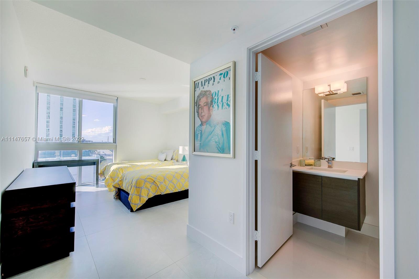 330 Sunny Isles Boulevard, Unit 5802 Sunny Isles Beach, FL 33160 - Photo 20 of 34 a spacious bedroom with a bed and a chandelier