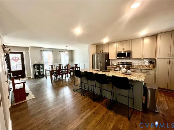 a kitchen with stainless steel appliances granite countertop a refrigerator a sink a stove a dining table and chairs