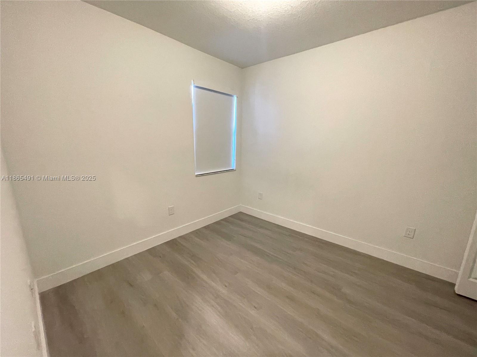 23269 Southwest 129th Path, Unit 23269 Miami, FL 33186 - Photo 16 of 20 a view of an empty room with wooden floor and a window