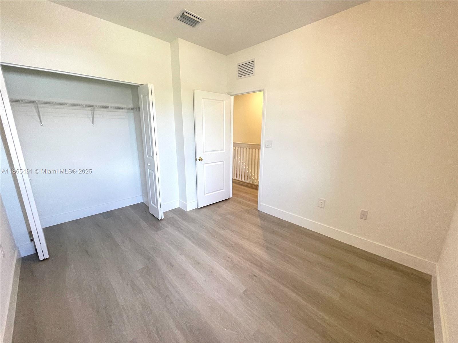 23269 Southwest 129th Path, Unit 23269 Miami, FL 33186 - Photo 20 of 20 an empty room with wooden floor and windows