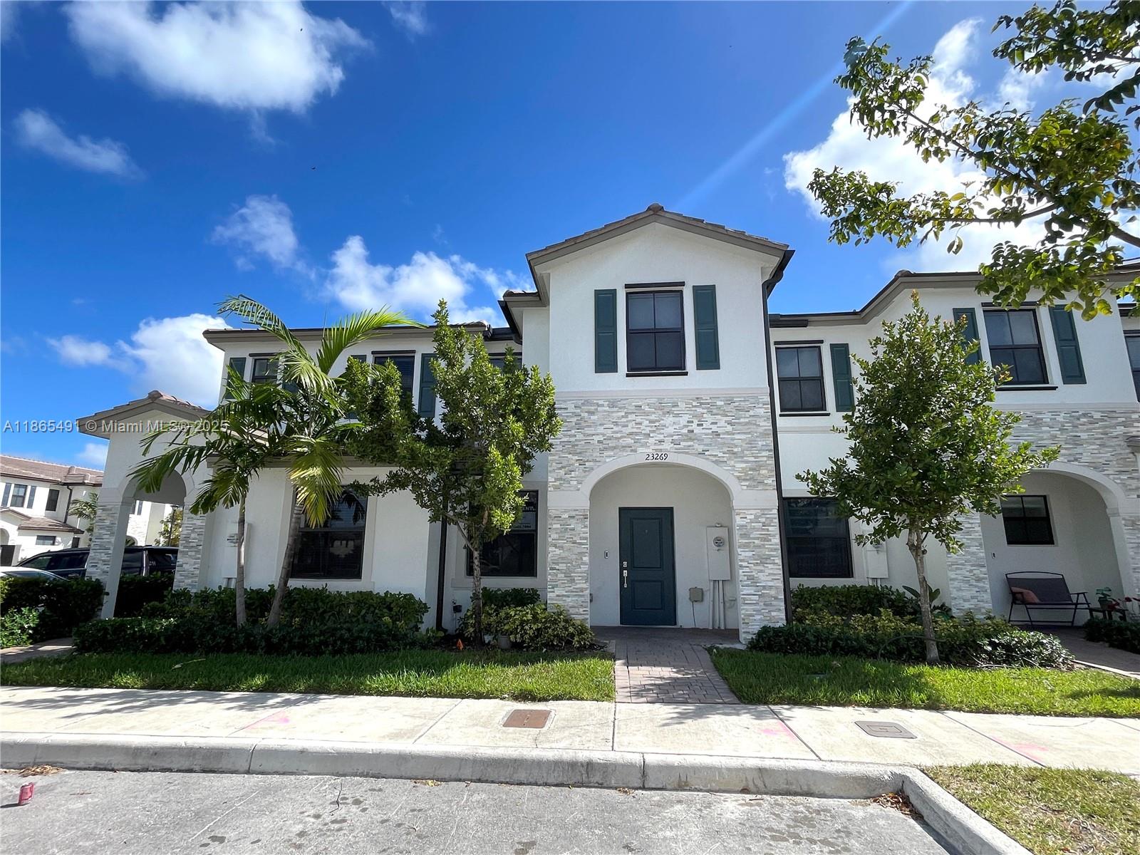 23269 Southwest 129th Path, Unit 23269 Miami, FL 33186 - Photo 2 of 20 a front view of a house with a yard and garage
