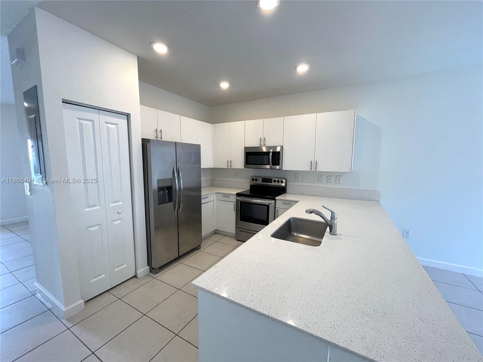 23269 Southwest 129th Path, Unit 23269 Miami, FL 33186 - Photo 5 of 20 a kitchen with a refrigerator a microwave and sink