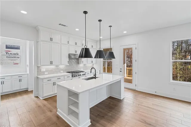 a large kitchen with kitchen island a stove a sink a center island and wooden floor