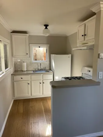 a kitchen with stainless steel appliances white cabinets and wooden floor
