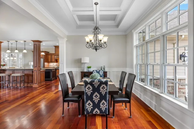 a dining room with wooden floor a chandelier a glass table and chairs