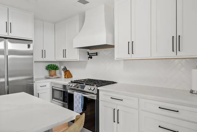 a kitchen with white cabinets and appliances