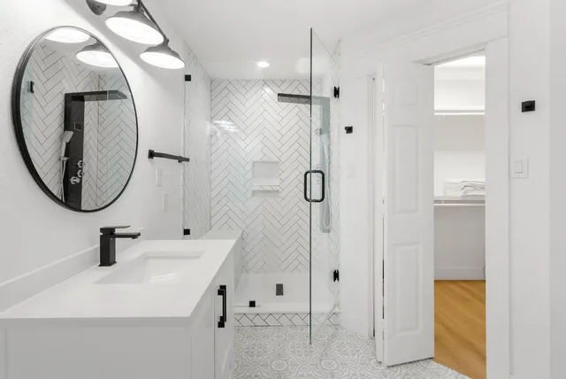 a bathroom with a sink a mirror a vanity and shower