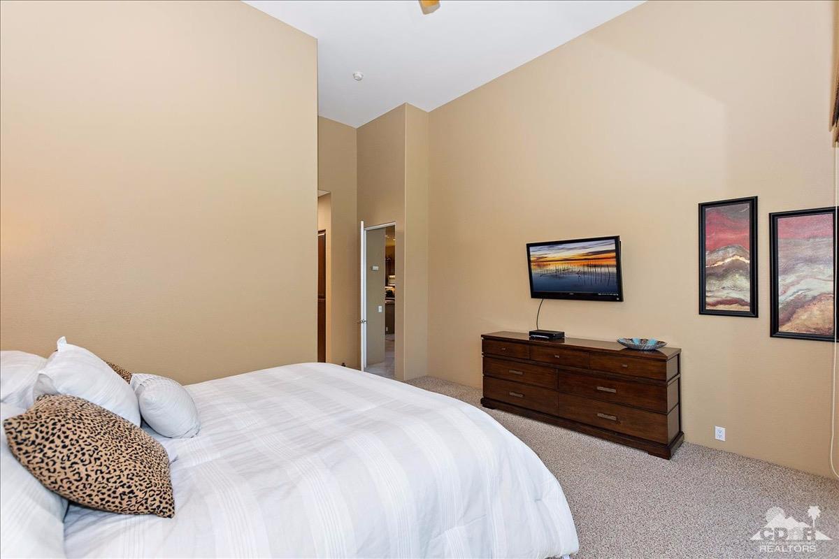 48010 Vía Vallarta La Quinta, CA 92253 - Photo 12 of 37 a bedroom with a bed and dresser with mirror
