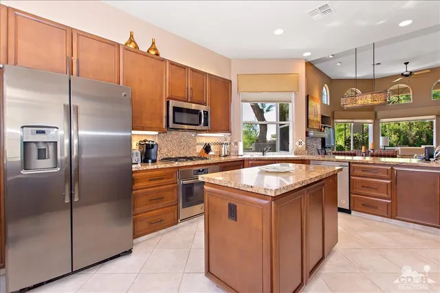 a kitchen with kitchen island granite countertop stainless steel appliances and a sink