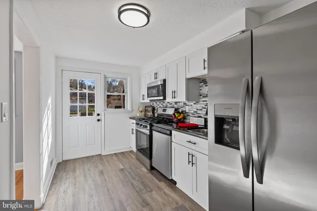 a kitchen with stainless steel appliances a refrigerator sink and white cabinets