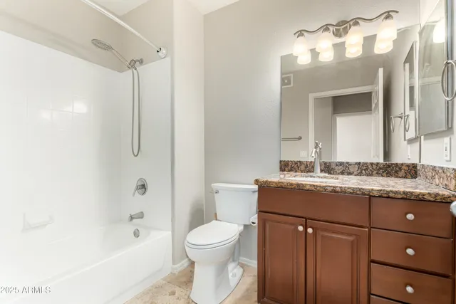 a bathroom with a granite countertop sink toilet mirror and a bathtub
