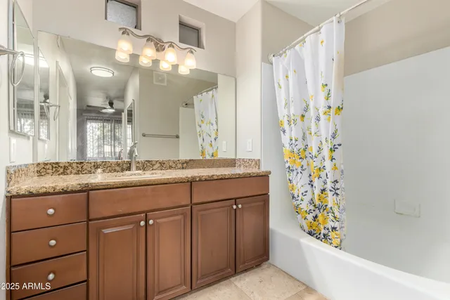 a bathroom with a granite countertop sink a mirror a vanity and a shower