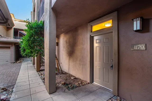 a view of a entryway door with plants in front of house