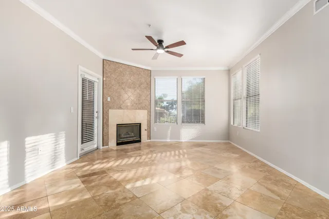 a view of a livingroom with a fireplace a ceiling fan and windows