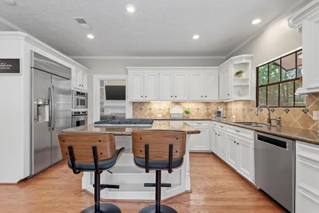 a kitchen with stainless steel appliances granite countertop a stove top oven a sink refrigerator and cabinets