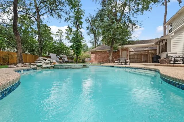 a view of a swimming pool with lawn chairs and plants