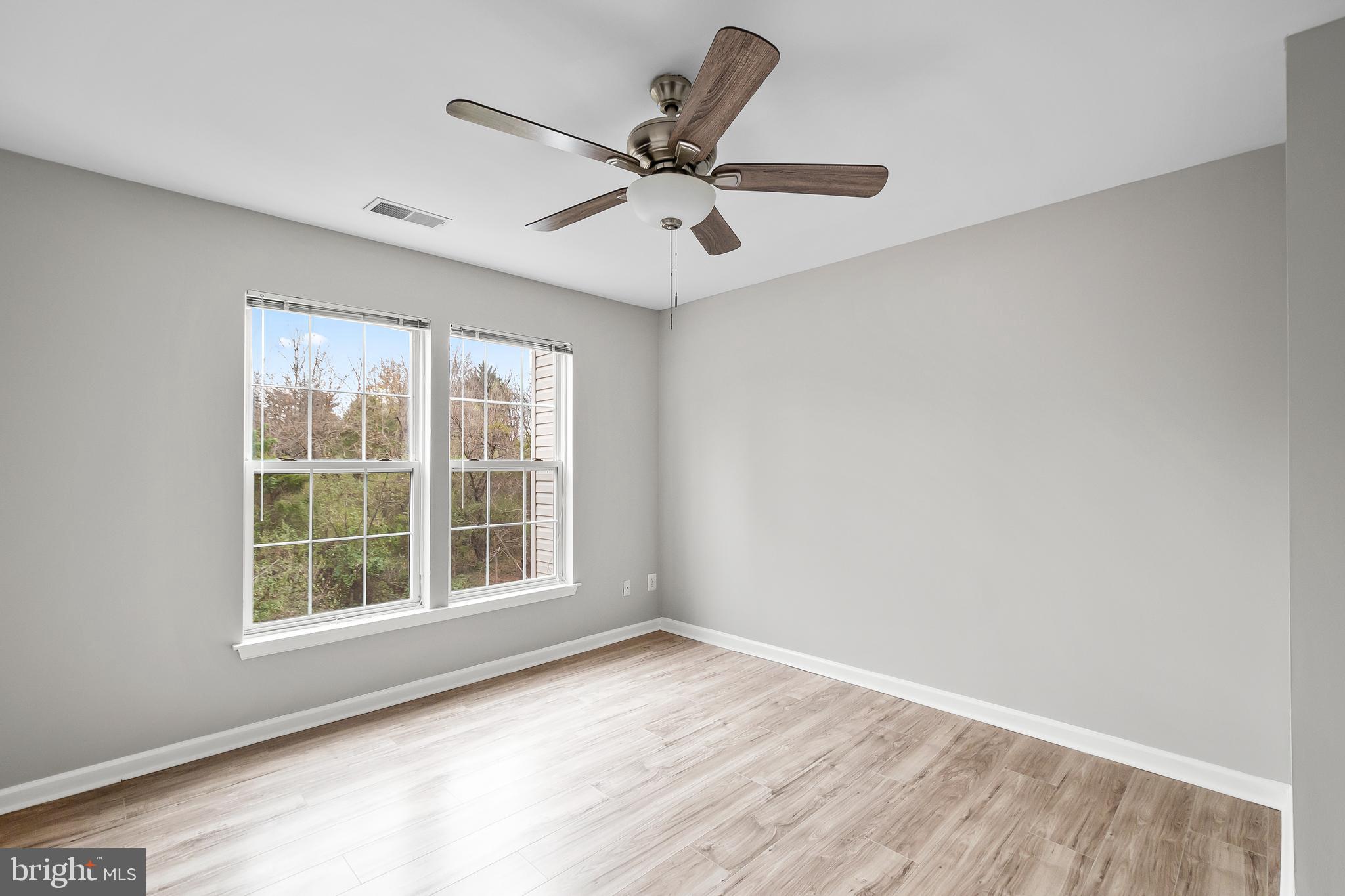 10305 Butternut Circle Manassas, VA 20110 - Photo 7 of 29 an empty room with wooden floor fan and windows