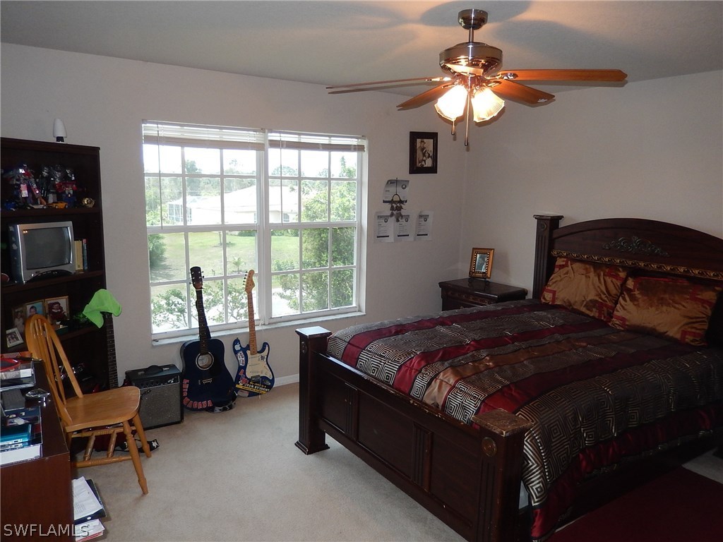 425 Jourferie Road Lehigh Acres, FL 33974 - Photo 21 of 25 a bedroom with a bed and a chandelier