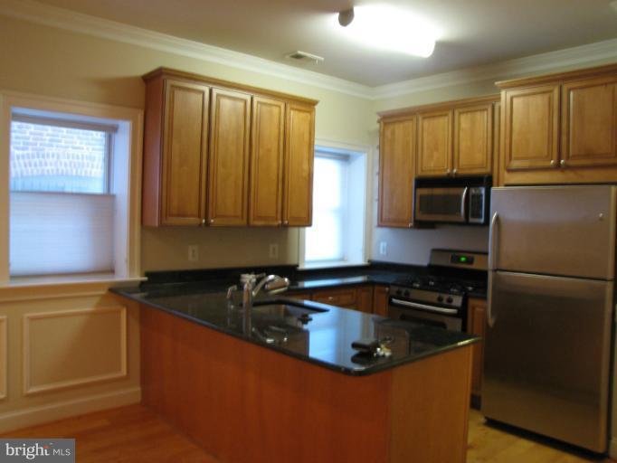 1740 18th Street Northwest, Unit 104 Washington, DC 20009 - Photo 9 of 13 a kitchen with sink a refrigerator and cabinets